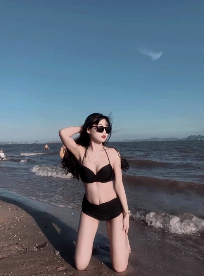 Cô gái trẻ trung diện bikini trắng dạo bước trên bãi cát vàng